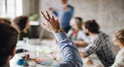 person raising his hand to ask a question in a business meeting