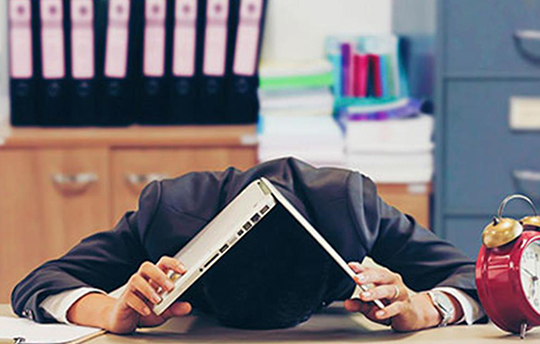 man in suit hiding his head under his laptop