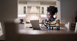 woman sitting at her dining room table at home looking at her laptop