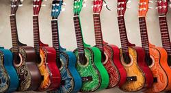 nine guitars in a range of different colors leaning against a wall