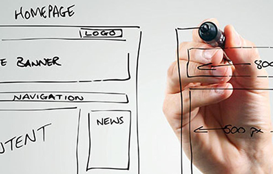 a hand with a marker drawing a webpage wireframe