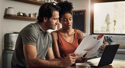 man and woman sitting together looking at paper work and a laptop