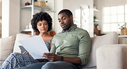 couple sitting together on couch looking at paperwork