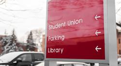 red sign at university that reads student union, parking, library