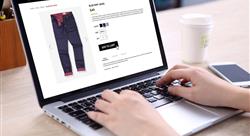 buying blue navy jeans on ecommerce website with smart phone, credit card and coffee on wooden desk