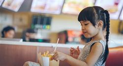 Young girl eating french fries at fast food restaurant