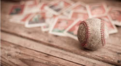 worn baseball on wooden bench with baseball cards blurred in the background
