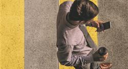 overhead view of a man walking across the street looking at his phone