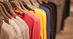 white, pink, and yellow sweaters hanging on a clothing rack