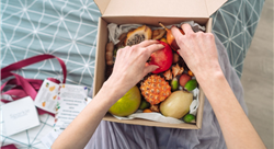 hands reaching into a box of fruit