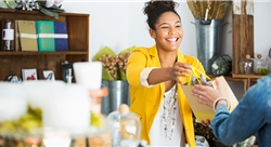 Smiling woman clerk handing a shopping bag to a customer