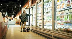 man at grocery store holding door open in the frozen aisle and reaching in