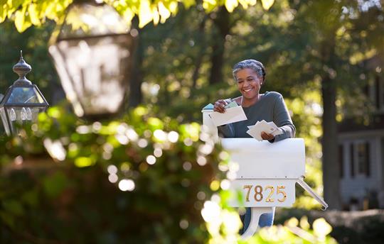 woman smiling at a personalized postcard