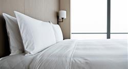 clean hotel bed with two white pillows and white sheets