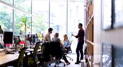 five business professionals in an open office setting having a discussion