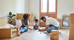 mom and dad with young child playing with small toys in the center of a room filled with moving boxes