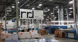 a large, open warehouse with large machines, boxes on pallets and a large canvas banner that says rrd retail solutions