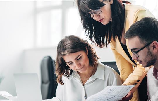 three supply chain coworkers reviewing print and digital communications