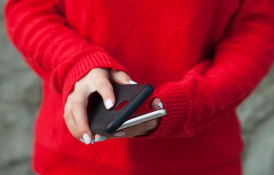 Person in red sweater putting protective case on smartphone