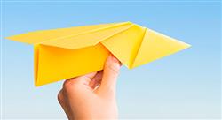 a hand holding a bright yellow paper airplane