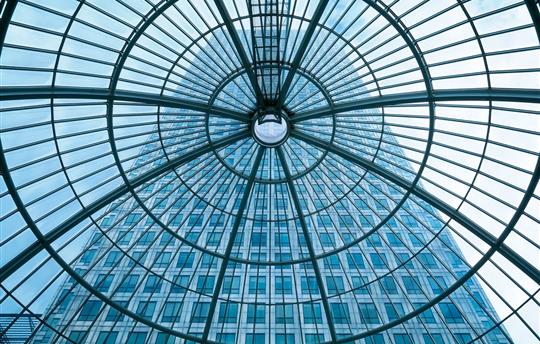 upward view of glass ceiling with a tall building in the background