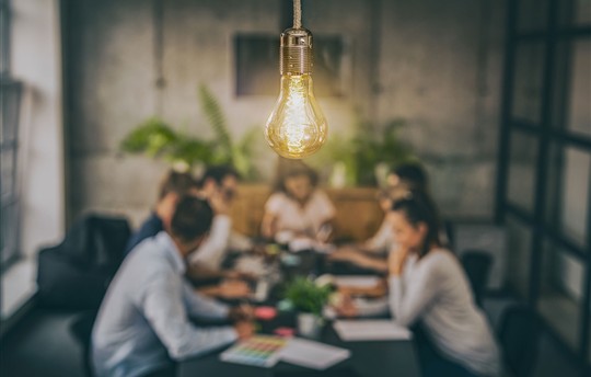 team meeting around a table with a light bulb hanging down