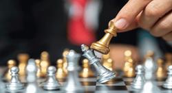 a silver and gold chess set where the gold queen is overtaking the silver king