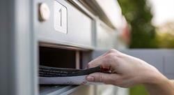 A hand removing mail from a mailbox
