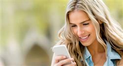 woman with blonde hair smiling as she looks at her smartphone